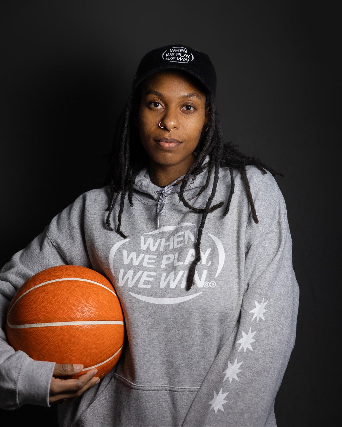 Person wearing a gray hoodie with a basketball, against a dark background